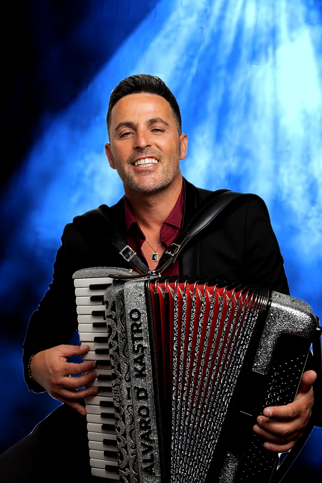 Fotografia oficial de ALVARO D'KASTRO com acordeão, em fundo azul